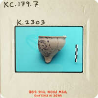 Ancient ceramic artifact with markings, photographed on a blue background and labeled with an identification number.