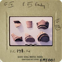 This is an image of ancient pottery shards with visible markings and designs, displayed on a white surface.