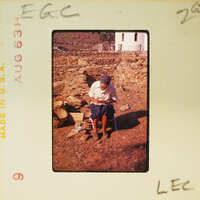 Woman sitting on a rock, looking at something in her hands.