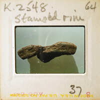 A photograph of a large, dark rock with jagged edges and a rough texture.