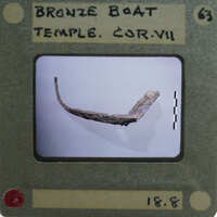 Ancient artifact, possibly a boat or temple part, displayed on a card with information and a barcode.