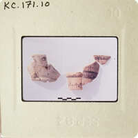 The image shows broken pieces of pottery on a white surface, with some fragments still intact and others shattered.