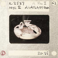 A photograph of a broken ancient Greek vase with visible shards and markings.