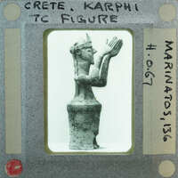 A black and white photo of a vintage figurine with writing on the border.