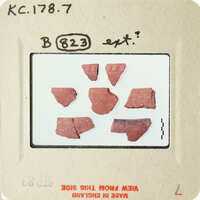 The image shows fragments of pottery on a white background, with handwritten labels and numbers indicating their identification.