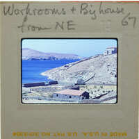 A slide of a coastal landscape with blue water, mountains, and buildings.