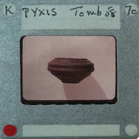 An image of a small, dark object on a light background with a film strip label that reads "MYXIS TOMB" and the year "70".