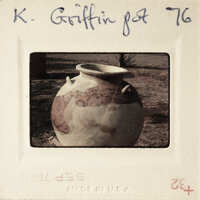 Ancient-looking clay pot with intricate designs on a sandy surface.