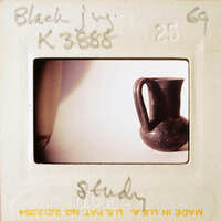 A photograph of a black vase on a white surface, with the word "STUDY" written on it.