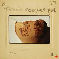 A photograph of an ancient tennis racket with intricate designs.