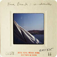 A photograph of an ocean scene with a windmill and mountains, taken from a boat.