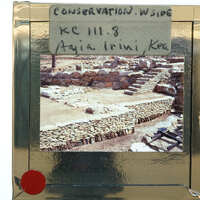 A slide of an ancient archaeological site with stone ruins and steps, displayed within a frame with handwritten labels.