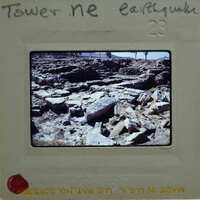 Old photo of an earthquake-damaged area with rocks and debris, enclosed in a film strip frame.