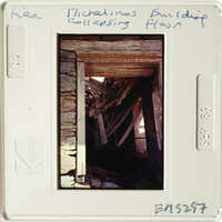 A photograph showing an old, weathered wooden structure with visible beams and stone elements.