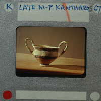 Ancient Greek vase displayed on a wooden surface.