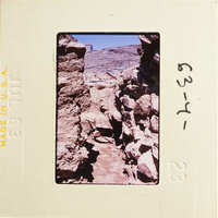 This is an image of ancient ruins with stone walls and rocks, set against a clear sky.