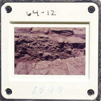 Photograph of rock formation with layers and embedded objects.