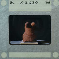 A photograph of a clay figurine with a dark background.