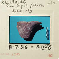 Old photograph of a broken pottery piece on a blue background with handwritten notes and measurements.