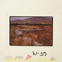 Old stone ruins in a dry landscape with mountains in the background.