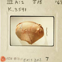 A cracked clay pot with visible lines and patterns, possibly ancient, photographed on a light background.