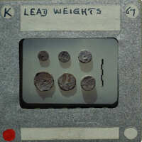 A collection of lead weights on a tray with labels and numbers written on it.
