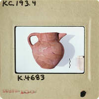 Ancient clay pot with visible cracks and imperfections on display.