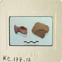 Two small clay figurines, possibly ancient pottery, displayed on a white surface with measurement lines and labels.