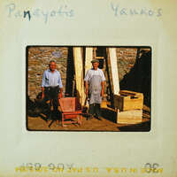 Two men standing next to a wooden structure and some lumber.