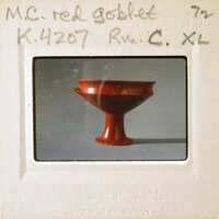 A red bowl with a handle on display.
