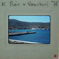 A vintage photo of a harbor with boats and hills in the background, encased in a film strip holder.