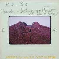 A close-up photo of a rock with a crack, taken from an angle that shows the texture and color variations.