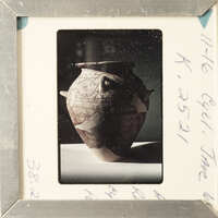 A framed photograph of a vase with intricate designs and a visible crack.