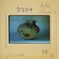 A yellow vase with floral designs on a white surface.