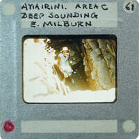 A vintage photo of a person in a cave with labels and numbers on the border.