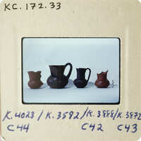 A collection of ancient vases displayed on a white surface.