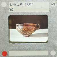 A photograph of an ornate ceramic cup on a white surface,