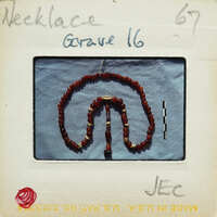 Red bead necklace with a gold pendant on a blue background, photographed on an old film negative.