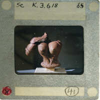 Terracotta figurine torso from front.