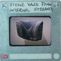 A photograph of a stone vase fragment with an intricate pattern on display.