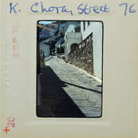 Old photograph of a narrow, cobblestone street with buildings on either side.