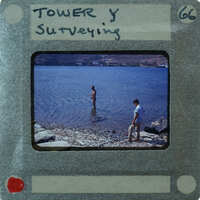 Two men fishing on a rocky shore near water.