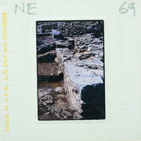 A photograph of an old stone wall with a film strip border and text.