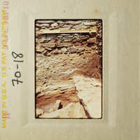 A photograph depicting an old, stone structure with a wooden frame and a date stamp.