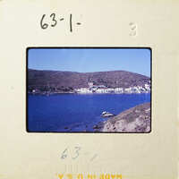 A photograph of a coastal village with houses and boats on the water, taken from an elevated perspective.
