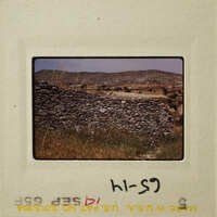A stone wall with mountains in the background, captured on an old photograph.