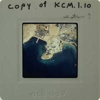 Aerial photograph of a coastal area with land and water, on a slide labeled "KMCL.1.10".