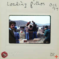 Group of people standing around a large clay pot outdoors, with mountains in the background.