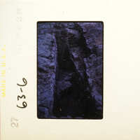 A photograph of an old, darkened slide with visible cracks and crevices.