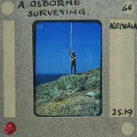 Man standing on rocky cliff with ocean below, captured in vintage Polaroid photo format.